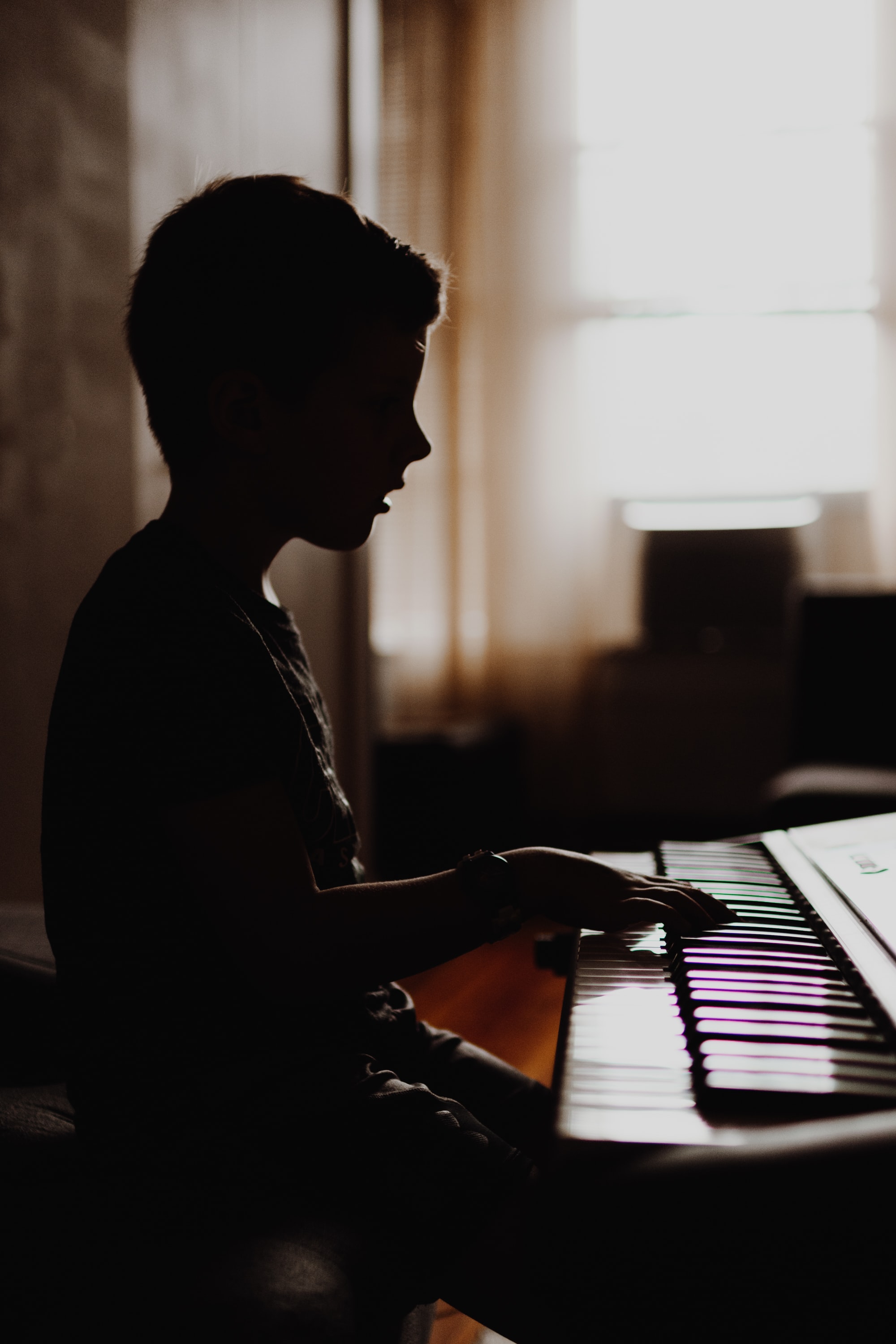 Sillouhette of a child sitting at a piano