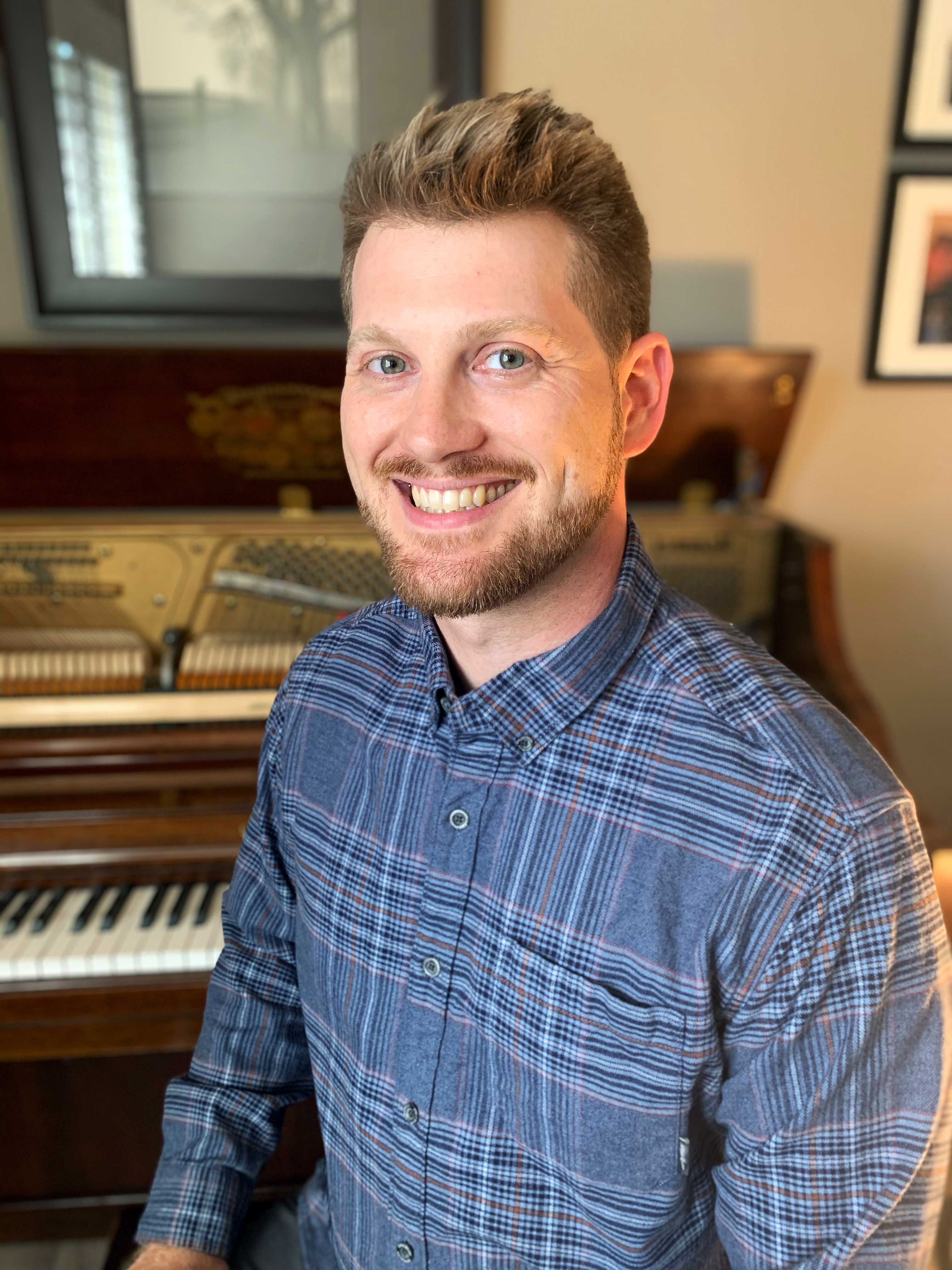 Dave Brisson smiling in front of a piano.